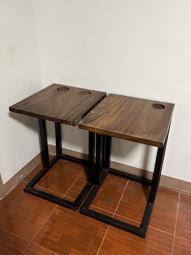 Wooden C-Shaped Side Table Set of Two (Category: Tables & Sets) located in Cabuyao City. Submitted by rdtrmt (Listing ID 1470990529, Image 1). Description: - Set of Two of Wooden C-shaped side table - Made of solid dark wood, natural wood grain top and a black metal frame - Crafted from thick, polished dark wood showing visible grain patterns, featuring built-in circular cup holders or recessed slots near the back edge. - Built with a geometric b
