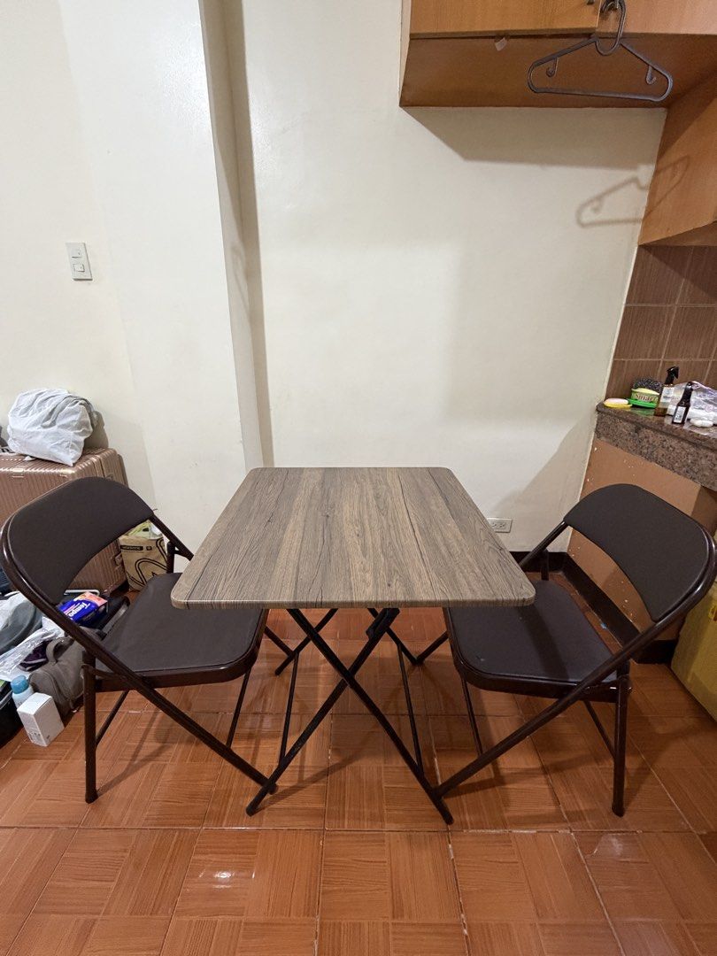 Wooden Table and Two Folding Chairs Set (Category: Tables & Sets) located in Manila. Submitted by shescarmeleve (Listing ID 1471078883, Image 2). Description: - Space-saving square folding table with wood-grain laminate top - Includes 2 matching brown folding chairs with comfortable padded seats - Durable dark metal frames on all pieces - Compact design, extremely easy to fold and store away - Condition: Light tear on one of the chair, still very