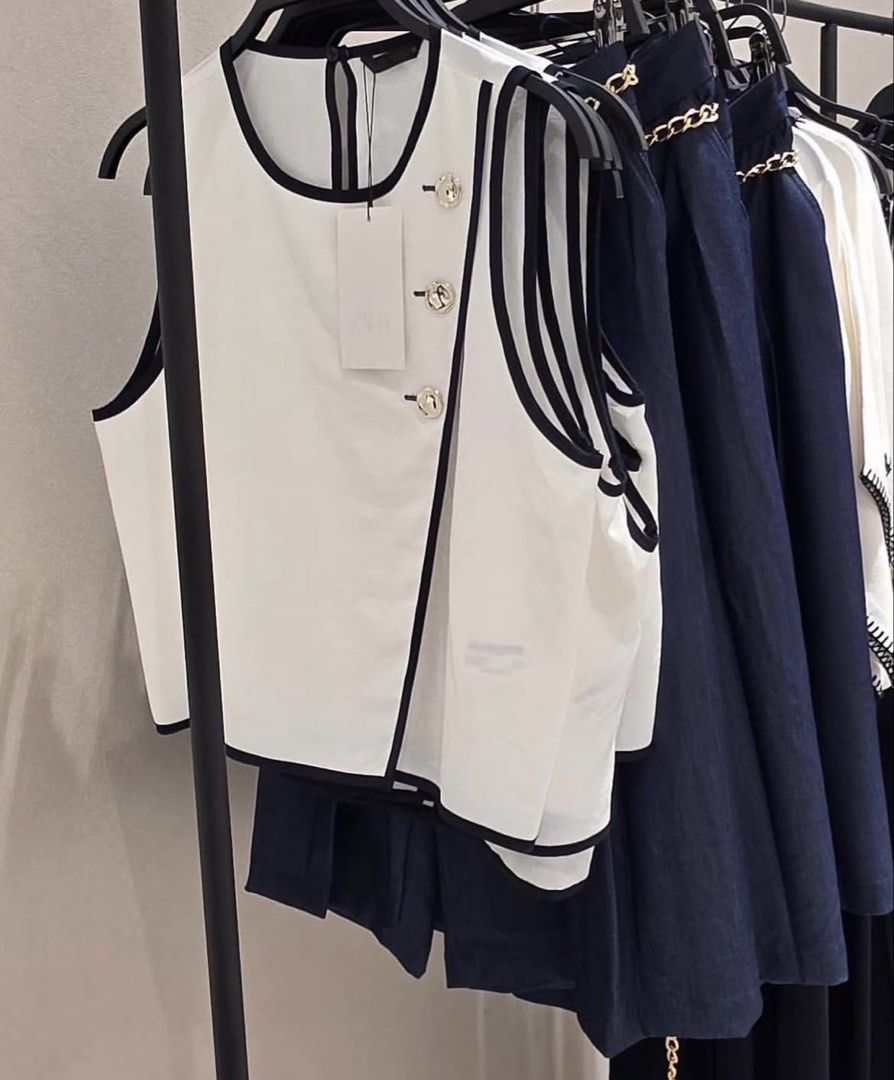 Zara Contrast Piping Top (Category: Sleeveless) located in Manila. Submitted by mazhktis.ndhdjssj79 (Listing ID 1470994562, Image 1). Description: - Size: S - Color: White with dark contrast piping - Design: Asymmetric front overlap with 3 metallic shoulder buttons - Material: Lightweight, clean-cut fabric - Perfect for smart-casual or chic everyday wear.