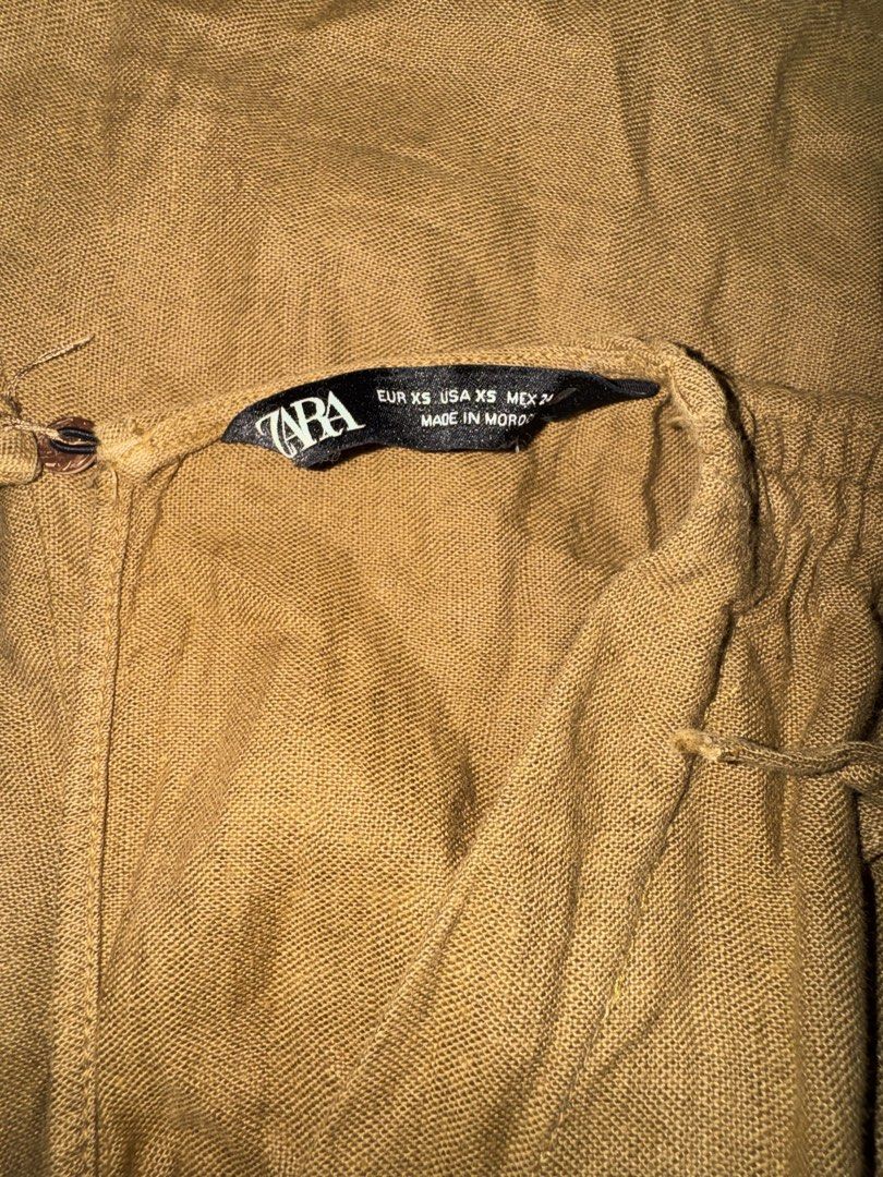 Zara mustard yellow linen romper playsuit (Category: Rompers) located in Manila. Submitted by maira_lucero (Listing ID 1471044954, Image 3). Description: - Brand: Zara - Size: XS - Color: Mustard Yellow - Material: Textured linen (Made in Morocco) - Design: Deep V-neckline with adjustable shoulder tie straps - Waist: Fitted with a matching self-tie back sash - Closure: Lower back zipper - Condition: Excellent, perfect for warm weather days.