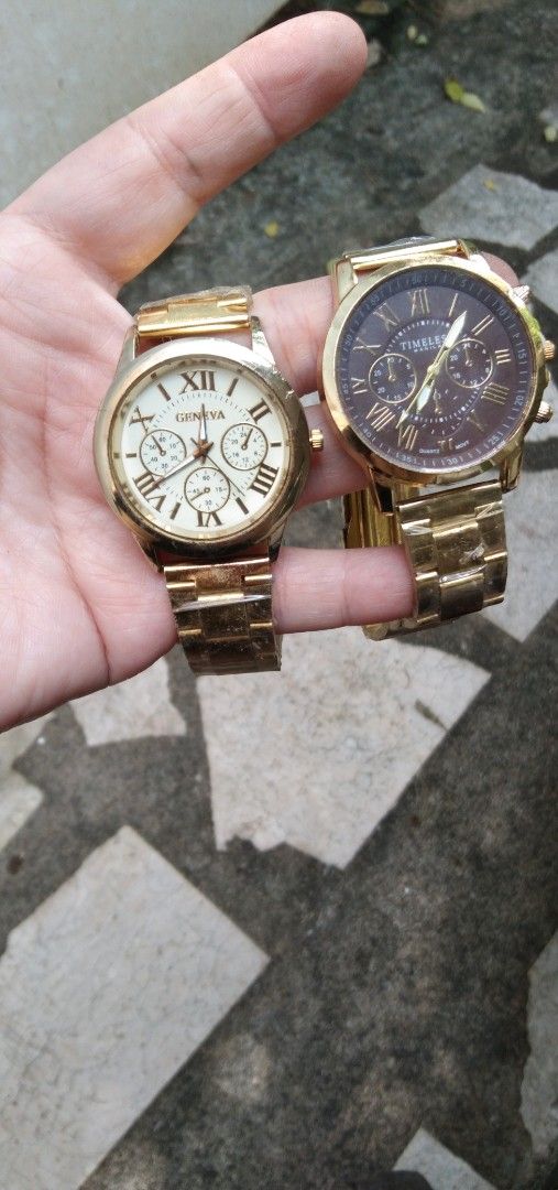 2 pcs watches Set old stock (Category: Women's Watches) located in Quezon City. Submitted by eidorableshop (Listing ID 1465703181, Image 1). Description: - Set of 2 brand new gold-tone wristwatches with protective plastic still attached - Left watch: Geneva brand, white dial, classic Roman numerals, and three decorative sub-dials - Right watch: Timeless Manila brand, rich dark brown dial with chronograph-style pushers - Straps: Matching metallic 