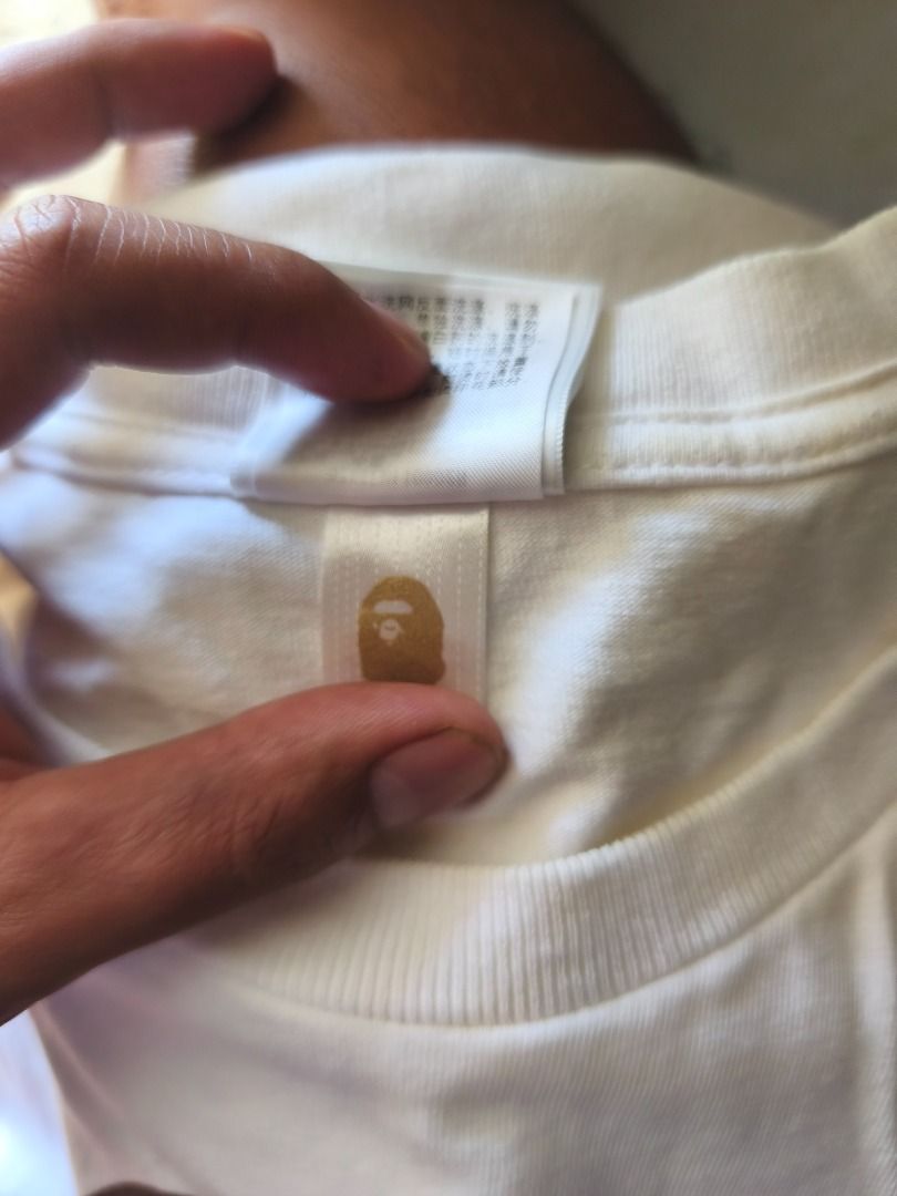 A Bathing Ape BAPE Ape Head White T-Shirt (Category: Tshirts & Polo Shirts ) located in Caloocan City. Submitted by neiledrian (Listing ID 1465727255, Image 3). Description: - Brand: A Bathing Ape (BAPE) - Color: Classic White - Design: Large brown and gold ape head print on the front - Size: Medium - Material: 100% cotton - Details: Yellow neck tag and standard interior wash tag included.