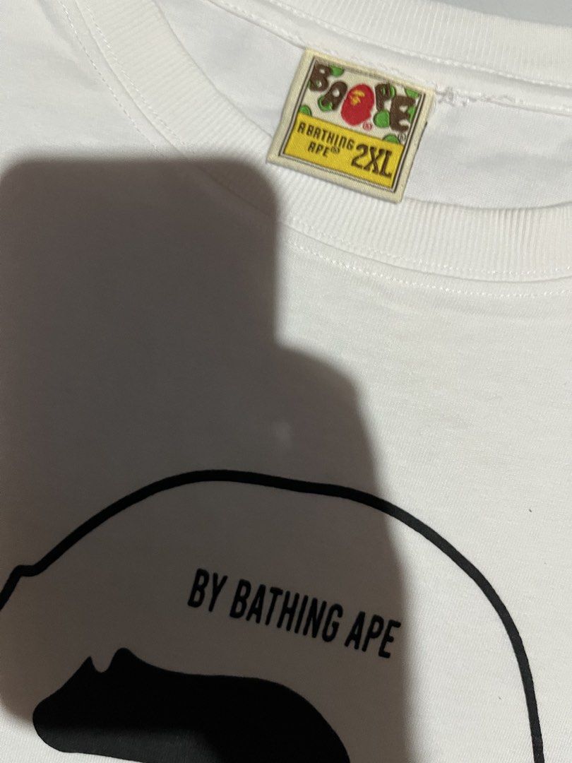 A Bathing Ape BAPE White Graphic Tee Size 2XL (Category: Tshirts & Polo Shirts ) located in Cavite. Submitted by christianzuuu (Listing ID 1465730432, Image 2). Description: - Dimes on actual photo - Brand: A Bathing Ape (BAPE) - Color: White - Size: 2XL (Measurements shown in photos) - Material: 100% Cotton - Design: Large Ape head graphic with 'Ape Shall Never Kill Ape' text - Condition: Brand new with classic collar and sleeve tags - Guarantee
