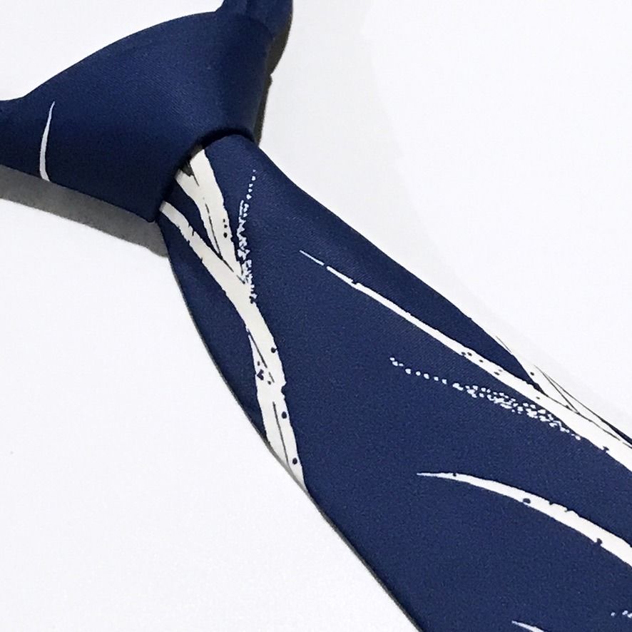 Access Floral Blue Neck Tie (Category: Ties) located in Taguig. Submitted by retrogaze (Listing ID 1465628985, Image 1). Description: This classic necktie by Access features a rich medium-blue base with a smooth twill weave finish. The body displays an artistic, Eastern-inspired floral motif with sweeping white-and-grey stalks, slender reed-like leaves, and soft grey blossom heads that extend upward along the blade. The reverse is finished with a