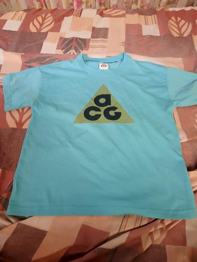 ACG NIKE (Category: Activewear) located in Odiongan. Submitted by thriftngo26 (Listing ID 1465644589, Image 1). Description: This is a light blue Nike ACG graphic t-shirt featuring the iconic triangular ACG (All Conditions Gear) logo on the chest.