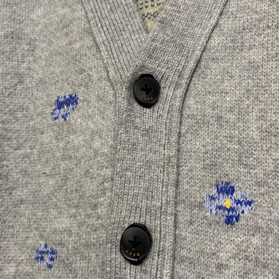 Ader Error Grey Wool Floral Cardigan Size A1 (Category: Coats, Jackets and Outerwear) located in Manila. Submitted by grapplers.gallery (Listing ID 1465742768, Image 2). Description: - Brand: Ader Error (2020 Season) - Item: Grey wool cardigan with all-over blue floral jacquard pattern and yellow center details - Material: 100% Wool - Size: A1 - Details: V-neck, button-up front with ADER branded buttons, and signature leather tag at the back neck