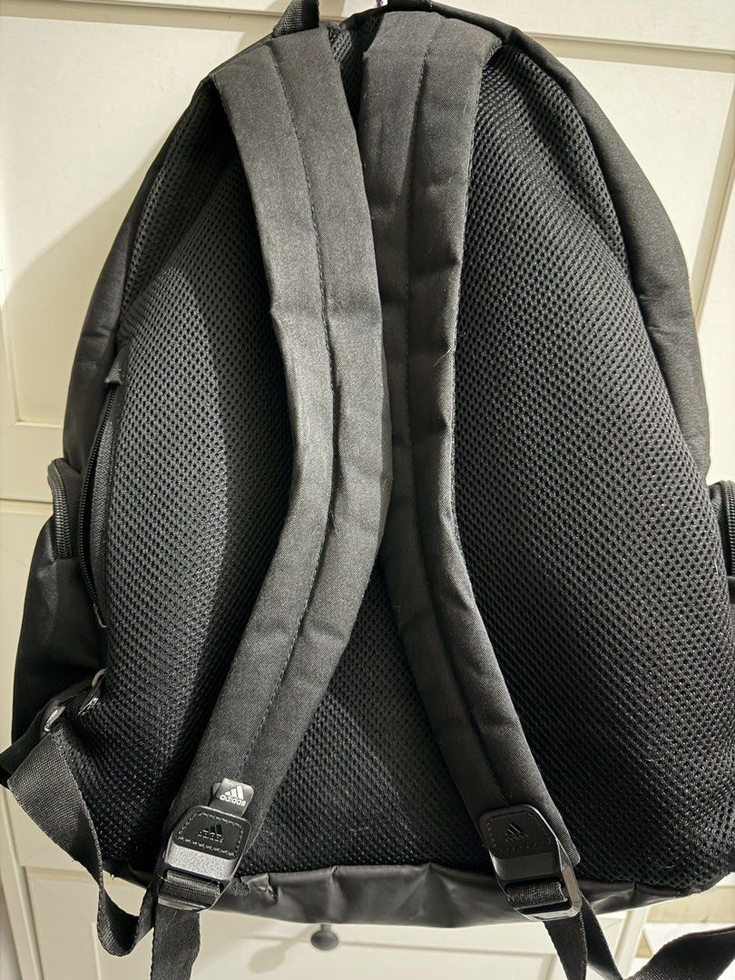 Adidas Black Backpack (Category: Backpacks) located in Santa Cruz. Submitted by fabfinds2024 (Listing ID 1465677241, Image 2). Description: Black Adidas backpack with a patterned stripe across the front pocket. Lower front section is made of textured material with an Adidas logo patch at the bottom corner. Breathable mesh padding on the back and shoulder straps. Inside has a lined main compartment with an internal sleeve pocket. Side zipper pocke
