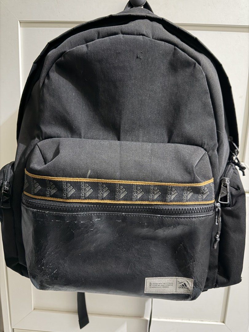 Adidas Black Backpack (Category: Backpacks) located in Santa Cruz. Submitted by fabfinds2024 (Listing ID 1465677241, Image 1). Description: Black Adidas backpack with a patterned stripe across the front pocket. Lower front section is made of textured material with an Adidas logo patch at the bottom corner. Breathable mesh padding on the back and shoulder straps. Inside has a lined main compartment with an internal sleeve pocket. Side zipper pocke