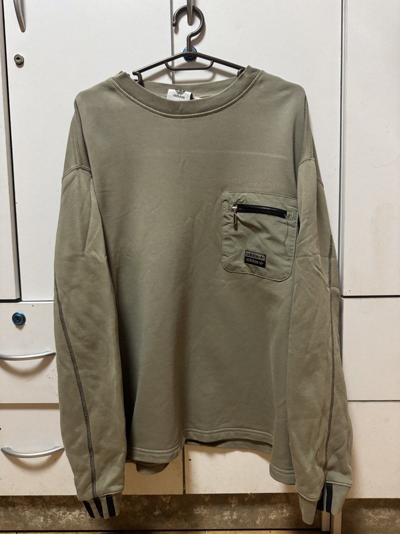 Adidas Pocketed Sweater (Category: Coats, Jackets and Outerwear) located in Manila. Submitted by quintessesommerset (Listing ID 1465664024, Image 1). Description: - Brand: Adidas Originals 24x28 - Color: Olive green - Fit: Relaxed, oversized streetwear style - Material: Heavy cotton blend with contrast dark sleeve stitching - Details: Zip-up utility pocket on left chest with double Adidas branding patches - Cuffs: Ribbed with subtle black and whi