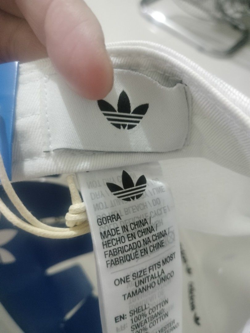 Adidas Trefoil White Baseball Cap Hat (Category: Caps & Hats) located in Imus. Submitted by emershop (Listing ID 1465648347, Image 3). Description: - Brand new with original tags still attached - Classic white design featuring a black embroidered Adidas trefoil logo - Made from 100% comfortable cotton for all-day wear - Adjustable back strap with subtle trefoil hardware for a custom fit - One size fits most with authentic blue inner branding tape
