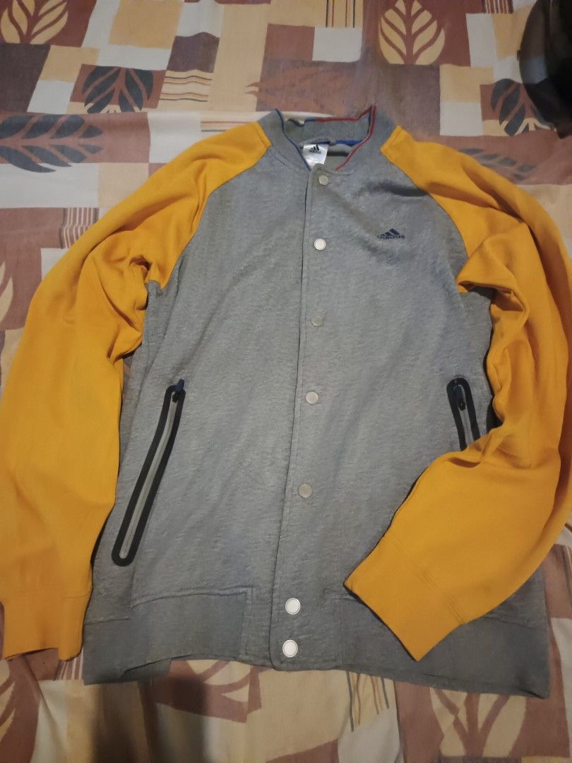 Adidas varsity jacket (Category: Activewear) located in Odiongan. Submitted by thriftngo26 (Listing ID 1465661846, Image 1). Description: appears to show an adidas gray and yellow snap-button knit baseball/varsity-style jacket with zippered side pockets..