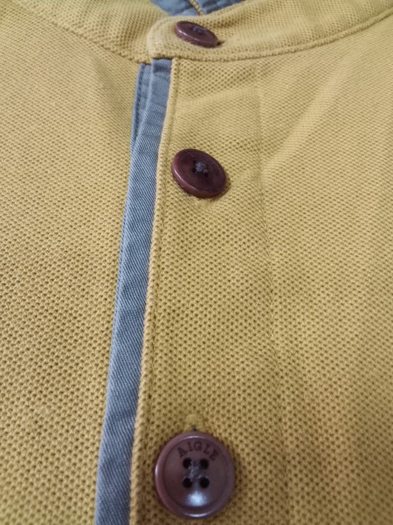 Aigle CT115 "EAGLETWIST" POLO SHIRT (Category: Tshirts & Polo Shirts ) located in Manila. Submitted by jctclthng_2026 (Listing ID 1465622683, Image 3). Description: - Brand: Aigle (Est. 1853) - Color: Mustard yellow with contrasting grey inner collar and placket - Material: Classic pique cotton fabric - Details: Three dark brown branded buttons, embroidered eagle logo on the left chest - Fit: Short sleeves, standard hem - Condition: Clean, well-m