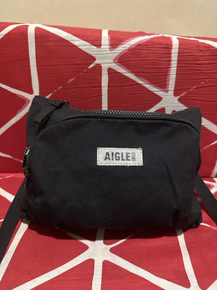 Aigle sling bag (Category: Sling Bags) located in Caloocan City. Submitted by hariel_beverly_onlineshop (Listing ID 1465688828, Image 1). Description: The item in the image is an Aigle crossbody / shoulder bag, featured in a minimalist matte black design. It is constructed from a lightweight, water-repellent nylon material typical of the brand’s practical outdoor and everyday travel gear. The bag features a rectangular silhouette with a main zipp