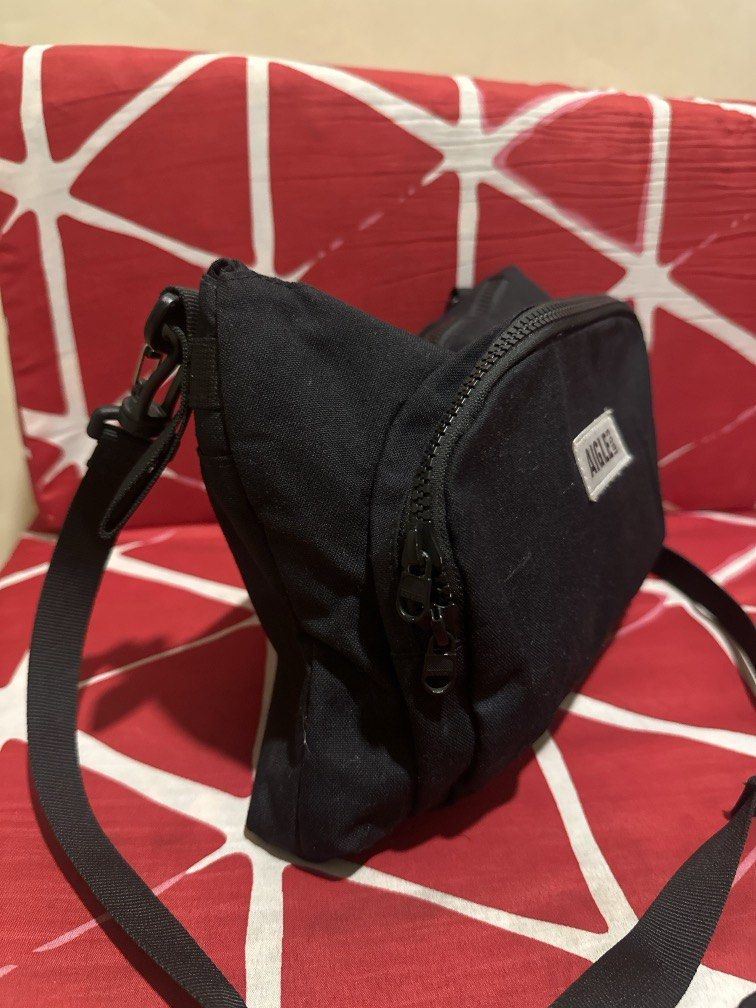 Aigle sling bag (Category: Sling Bags) located in Caloocan City. Submitted by hariel_beverly_onlineshop (Listing ID 1465688828, Image 3). Description: The item in the image is an Aigle crossbody / shoulder bag, featured in a minimalist matte black design. It is constructed from a lightweight, water-repellent nylon material typical of the brand’s practical outdoor and everyday travel gear. The bag features a rectangular silhouette with a main zipp