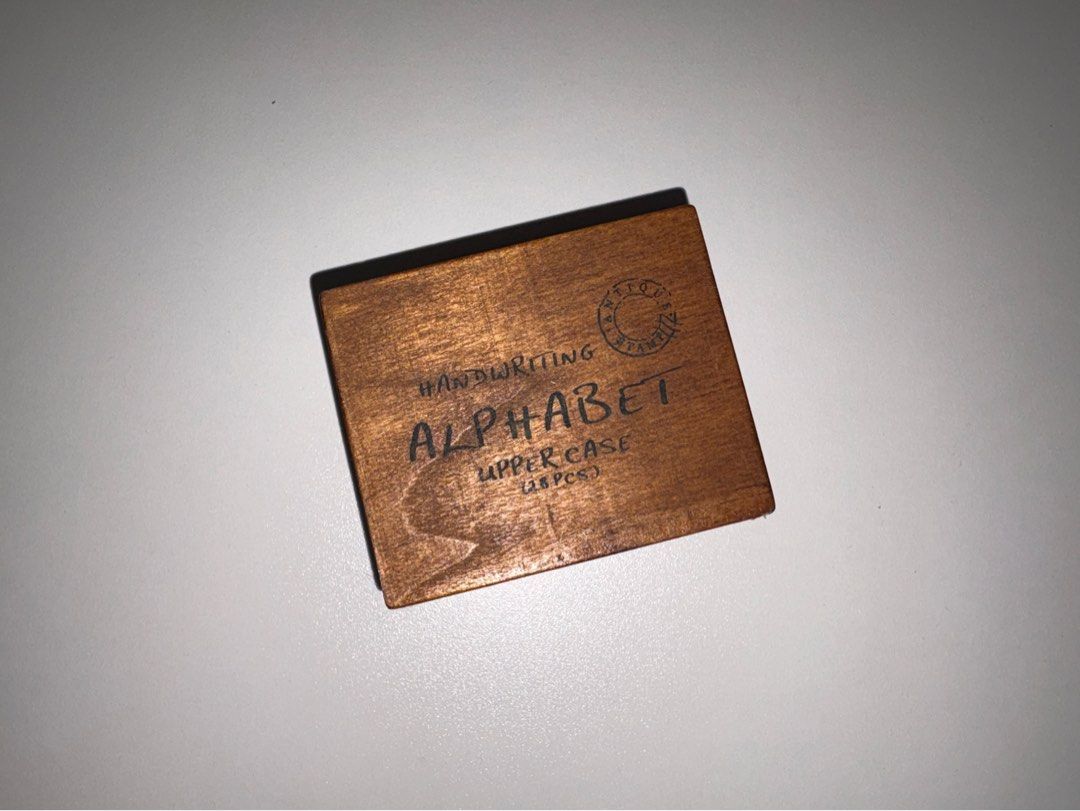 Alphabet Stamp Set (Category: Craft Supplies & Tools) located in Quezon City. Submitted by vvelcometomyshop (Listing ID 1465755141, Image 2). Description: - Set includes 28 wooden stamps with uppercase letters and punctuation marks - Neatly packed in a matching wooden storage box with a convenient sliding lid - Features a charming antique stamp logo and 'Handwriting Alphabet Upper Case' text on the lid - Ideal for scrapbooking, bullet journaling,