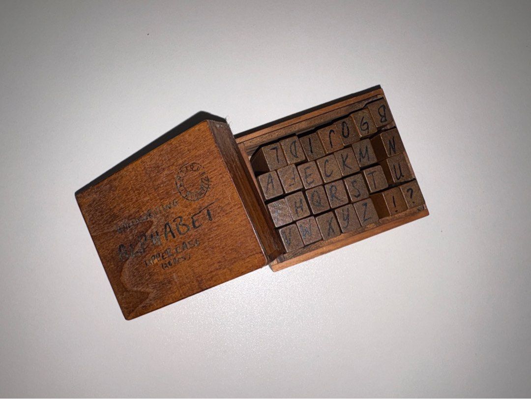 Alphabet Stamp Set (Category: Craft Supplies & Tools) located in Quezon City. Submitted by vvelcometomyshop (Listing ID 1465755141, Image 1). Description: - Set includes 28 wooden stamps with uppercase letters and punctuation marks - Neatly packed in a matching wooden storage box with a convenient sliding lid - Features a charming antique stamp logo and 'Handwriting Alphabet Upper Case' text on the lid - Ideal for scrapbooking, bullet journaling,