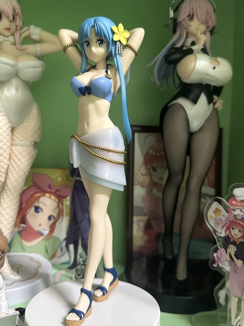 Asuna figure (Category: Figurines & Statues) located in Manila. Submitted by silentfire.54ea36 (Listing ID 1465750374, Image 1). Description: - Character: Anime figure with iconic long blue pigtails and a yellow flower accessory - Outfit: Light blue two-piece swimsuit and white sarong with elegant gold beaded trim - Footwear & Base: Blue strapped sandals, securely mounted on a clean white base - Pose: Playful pose with hands raised behind her hea