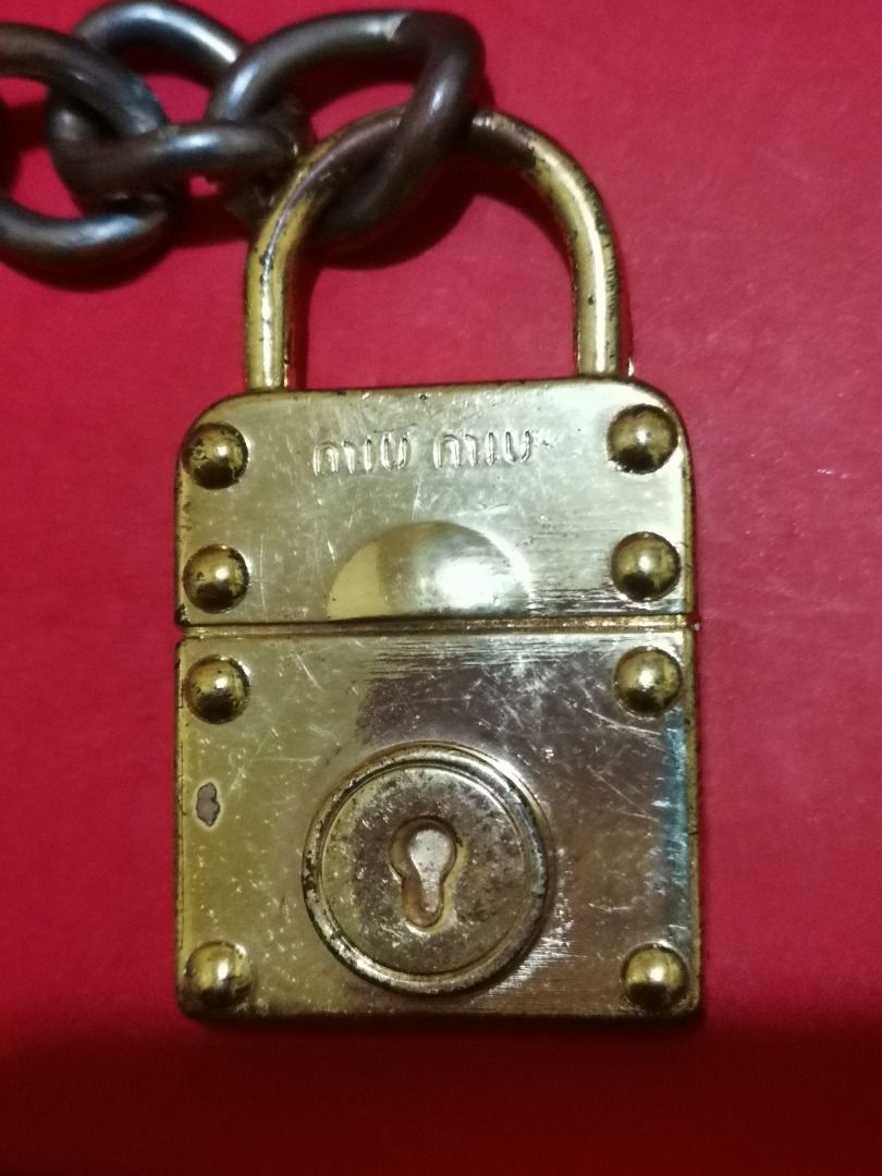Authentic Miu Miu Padlock and Key Charm (Category: Charms) located in Caloocan City. Submitted by 23jkp (Listing ID 1465715298, Image 2). Description: - Authentic Miu Miu padlock and matching key charm set - Elegant gold-tone finish with textured panels and embossed logo details - Comes with a dark metal chain link attachment for easy styling - Condition: Good, with minor surface scratches and light tarnish on hardware - Perfect for customizing y