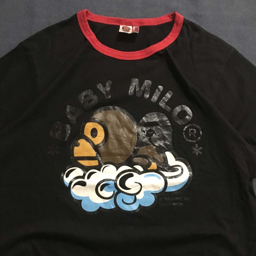Baby Milo by A Bathing Ape Ringer Tee (Category: Shirts) located in Manila. Submitted by its_d4ve (Listing ID 1465688093, Image 2). Description: - Brand: Baby Milo - Color: Black with red ribbed collar and sleeve cuffs - Size: Large - Material: 100% Cotton - Design: Large Baby Milo sitting on clouds graphic on chest - Detailing: Small white Baby Milo logo on upper back neckline - Condition: Excellent / Pre-loved - Mode of Payment: GCash or BPI - 