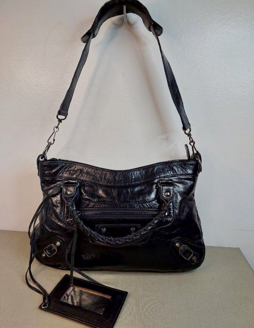 Balenciaga Black Leather Shoulder Bag (Category: Shoulder Bags) located in Bacacay. Submitted by jpbellen80790 (Listing ID 1465582238, Image 1). Description: CODED and LAMPO - Style: Black crinkled leather shoulder bag - Handles: Braided top handles plus a detachable shoulder strap - Details: Front zip pocket with hardware studs and buckled corner accents - leather pocket mirror on leather tassels - Fit: Perfect everyday size that goes with liter