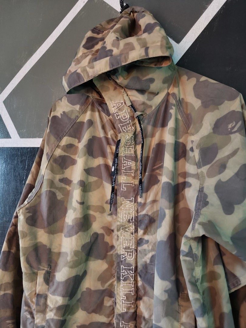 BAPE Kids Camo Windbreaker Jacket (Category: Coats, Jackets and Outerwear) located in Manila. Submitted by choycleverdeer.f04b80 (Listing ID 1465630889, Image 3). Description: - A BAPE Kids Camo Windbreaker - Size: XL - Design: Classic green & brown camo with hidden Ape Head graphics - Details: Large 'APE SHALL NEVER KILL APE' text on front placket & branded drawstrings - Features: Hooded, zip-up front with snap buttons at hem and cuffs, plus sid