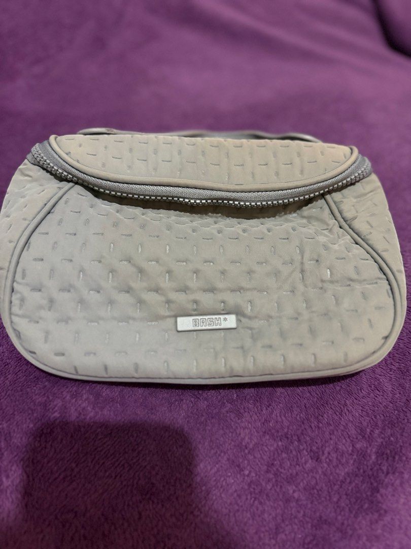 BASH BILLOW ORGANIZER IN STONE (Category: Purses & Pouches) located in Mandaluyong City. Submitted by merzypreloved (Listing ID 1465718395, Image 1). Description: - Brand: BASH - Color: Stone - Design: Chic quilted dash pattern all over with a structured shape - Closure: Wide-opening top zip for easy access - Organization: Built-in flap section featuring an elastic band and slip slots for makeup brushes - Portability: Convenient handle strap atta
