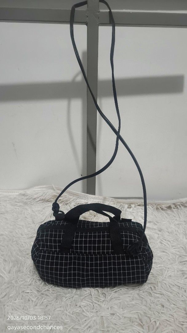 BBC Made in U.S.A. BLACK GRID MINI DUFFEL BAG (Category: Luxury Bags & Wallets) located in Kalibo. Submitted by secondchances.thriftsh8p (Listing ID 1465691239, Image 2). Description: - Color & Pattern: Black with a white grid pattern - Brand detail: Woven black label with 'BBC Made in U.S.A.' in gold lettering - Design: Trendy small barrel shape with dual top carry handles - Strap: Long, thin shoulder strap attached with durable metal rings - Cl
