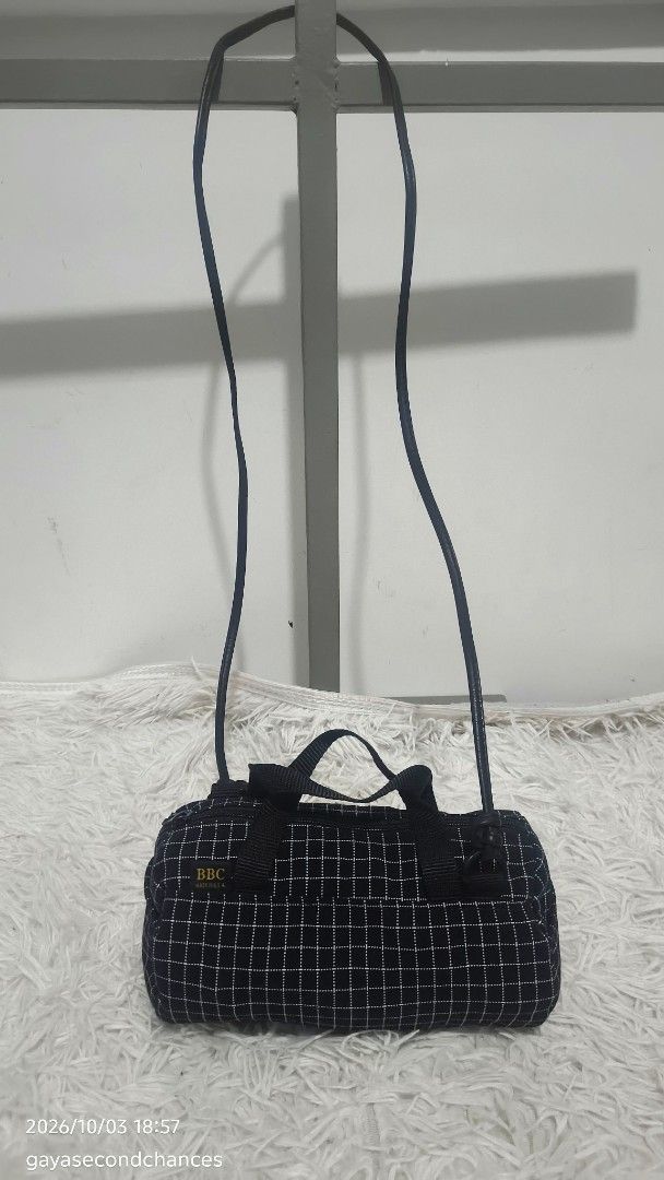BBC Made in U.S.A. BLACK GRID MINI DUFFEL BAG (Category: Luxury Bags & Wallets) located in Kalibo. Submitted by secondchances.thriftsh8p (Listing ID 1465691239, Image 1). Description: - Color & Pattern: Black with a white grid pattern - Brand detail: Woven black label with 'BBC Made in U.S.A.' in gold lettering - Design: Trendy small barrel shape with dual top carry handles - Strap: Long, thin shoulder strap attached with durable metal rings - Cl