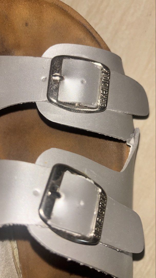 Birkenstock Two-Strap Sandals Silver (Category: Flats & Sandals) located in Manila. Submitted by cheetosjalapeno.f6b498 (Listing ID 1465709859, Image 3). Description: - Authentic silver Birkenstock sandals - Features two adjustable metal buckles with engraved brand name - Classic cork footbed with brand logo stamp - Smooth synthetic upper material - Condition note: Footbed shows noticeable wear and dark discoloration from regular use, but fully f