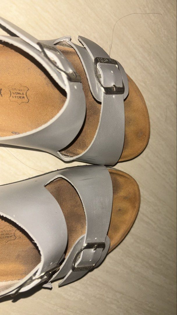 Birkenstock Two-Strap Sandals Silver (Category: Flats & Sandals) located in Manila. Submitted by cheetosjalapeno.f6b498 (Listing ID 1465709859, Image 2). Description: - Authentic silver Birkenstock sandals - Features two adjustable metal buckles with engraved brand name - Classic cork footbed with brand logo stamp - Smooth synthetic upper material - Condition note: Footbed shows noticeable wear and dark discoloration from regular use, but fully f