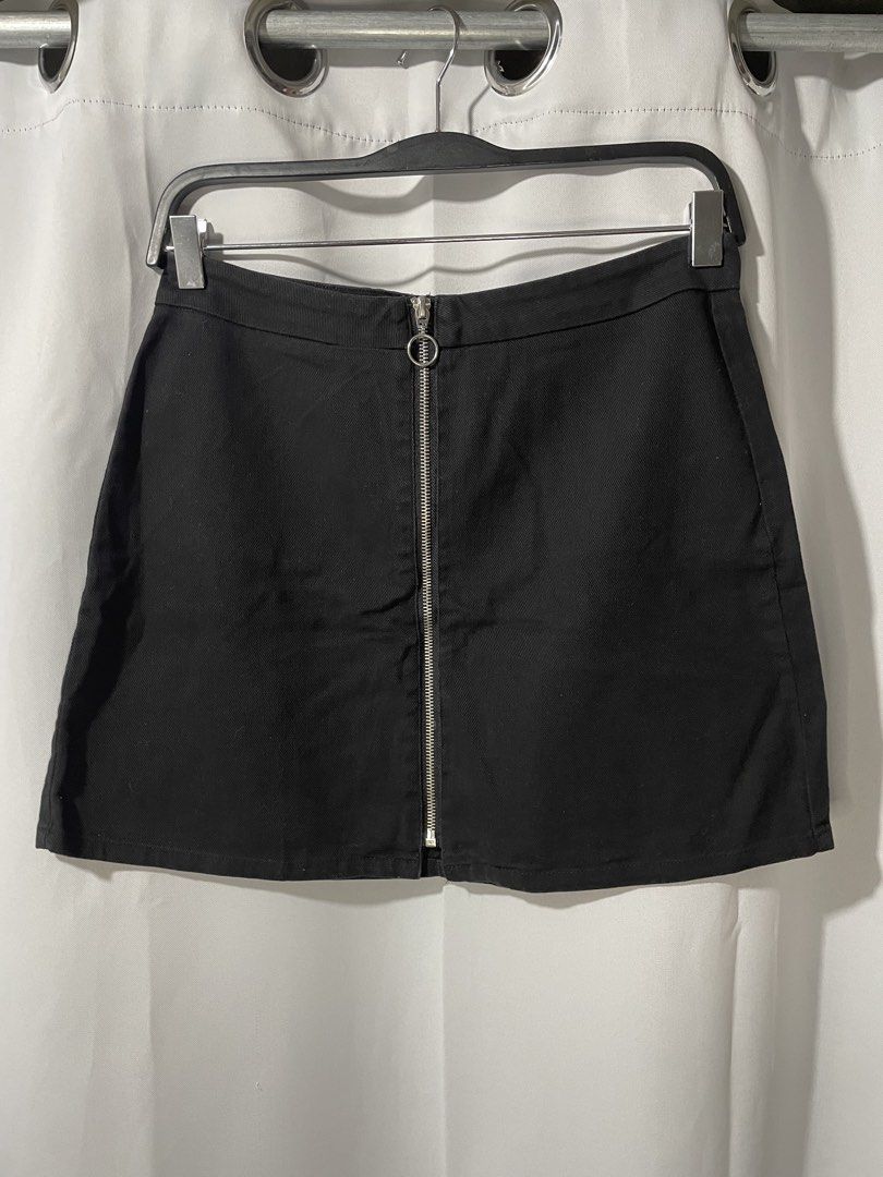 Black denim mini skirt with front zip (Category: Skirts) located in Bacoor. Submitted by prelovedbyphaty (Listing ID 1465582899, Image 1). Description: - Color: Solid black - Material: Denim - Fit: Mid-rise, A-line shape, hits above the knee - Closure: Front zipper with silver circle pull ring - Styling: Versatile staple piece, easy to dress up or down with tees, sweaters, or tanks.