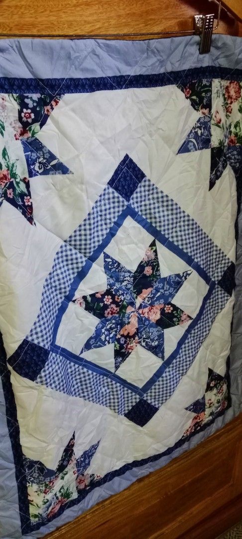 Blue and White Patchwork Quilt with Star Pattern Long Pillowcase (Category: Bedding & Towels) located in Mangaldan. Submitted by closetqwin (Listing ID 1465648168, Image 2). Description: Vintage Pillowcase never been used -Size 29.5 inches Length and 22.5 inches Width - Features a striking central star pattern with checkered borders and floral corner stars - Soft quilted texture with a solid light blue backing and border trim.