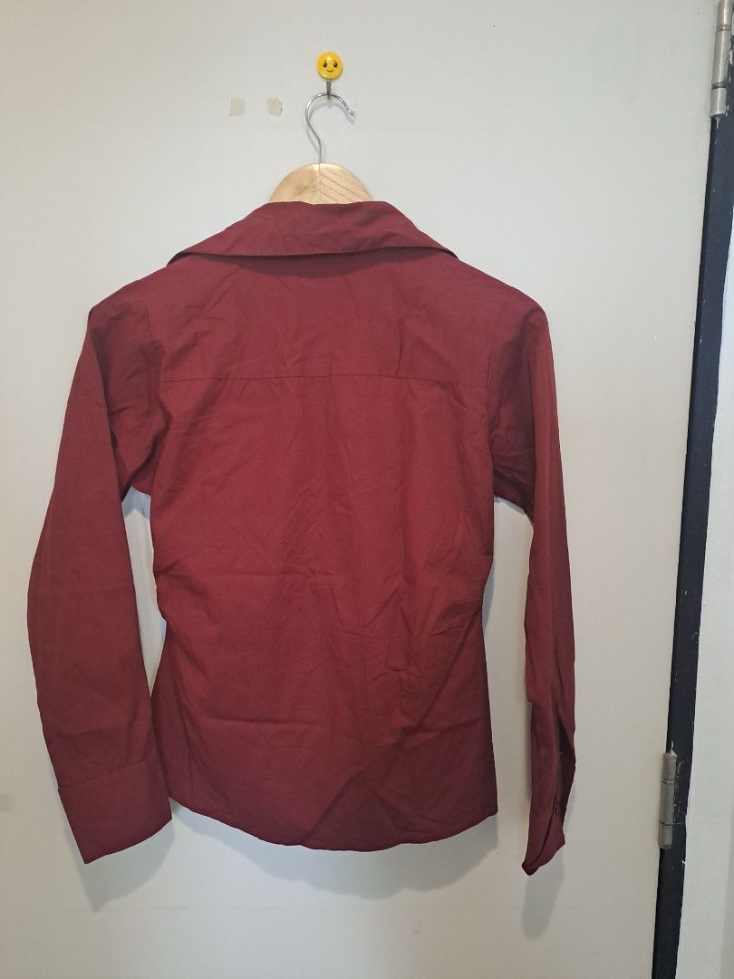 Burgundy ruched longsleve (Category: Longsleeves) located in Manila. Submitted by joanbalde39643 (Listing ID 1465603699, Image 2). Description: This item is a burgundy ruched button-down shirt featuring a sharp, pointed collar and a fitted, waist-cinching silhouette. The front panel is detailed with vertical ruching along the central button placket, creating a sculpted structure reminiscent of the "office siren" and Y2K aesthetics..