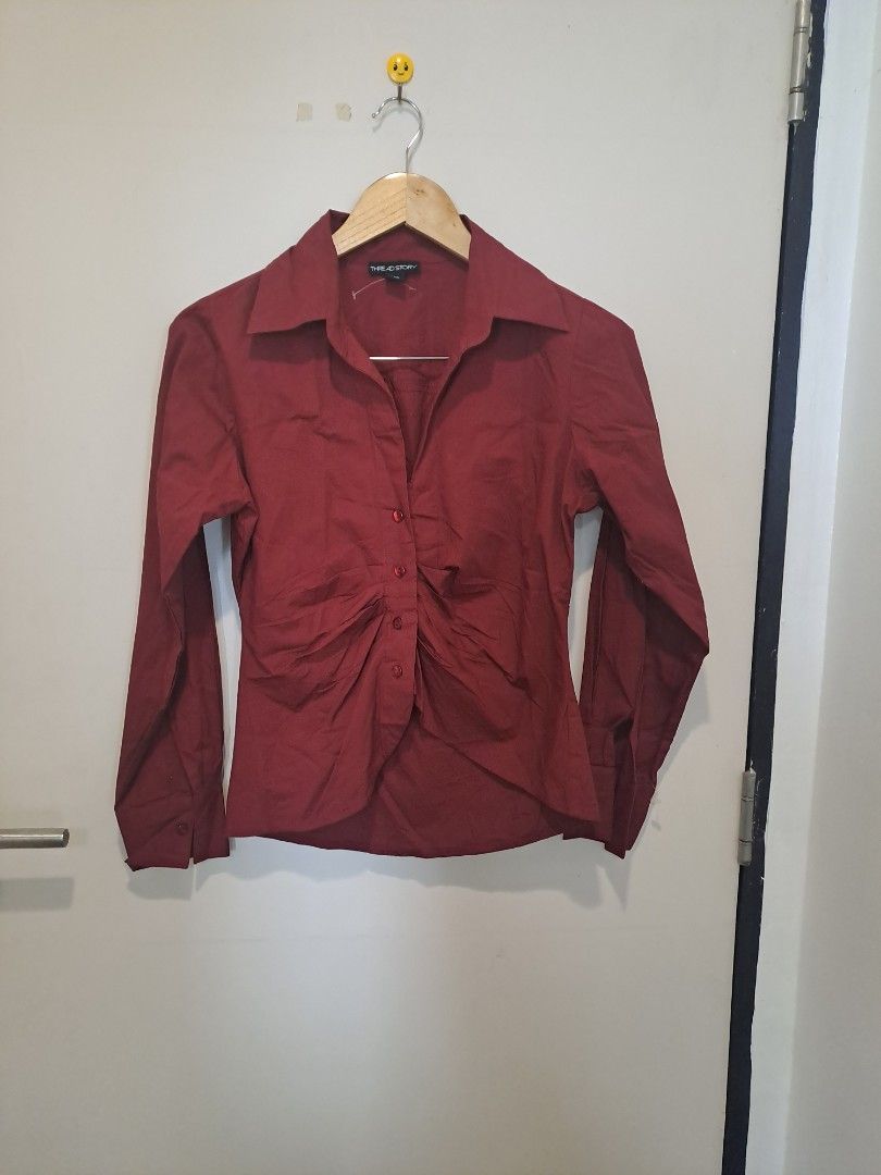 Burgundy ruched longsleve (Category: Longsleeves) located in Manila. Submitted by joanbalde39643 (Listing ID 1465603699, Image 1). Description: This item is a burgundy ruched button-down shirt featuring a sharp, pointed collar and a fitted, waist-cinching silhouette. The front panel is detailed with vertical ruching along the central button placket, creating a sculpted structure reminiscent of the "office siren" and Y2K aesthetics..
