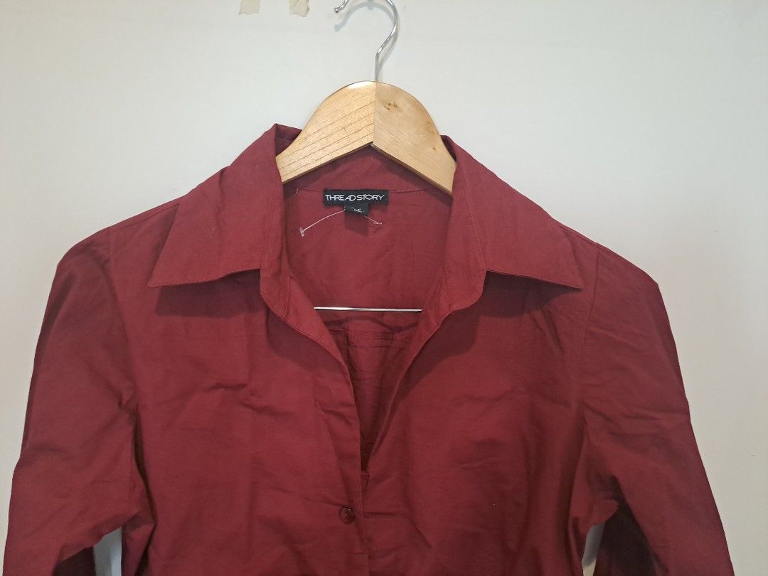 Burgundy ruched longsleve (Category: Longsleeves) located in Manila. Submitted by joanbalde39643 (Listing ID 1465603699, Image 3). Description: This item is a burgundy ruched button-down shirt featuring a sharp, pointed collar and a fitted, waist-cinching silhouette. The front panel is detailed with vertical ruching along the central button placket, creating a sculpted structure reminiscent of the "office siren" and Y2K aesthetics..