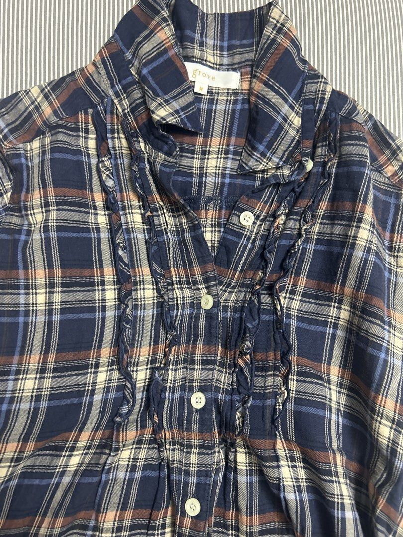 Button up blouse (Category: Blouses) located in Singapore. Submitted by swaninlouboutins (Listing ID 1465698313, Image 3). Description: Size: S to M ptp: 47.5 cm length: 69 cm - Material: Soft flannel-like fabric - Features: Short sleeves, button-front closure, classic collar, and stylish ruffle trim down the chest - Condition: Great for casual everyday wear or layering.