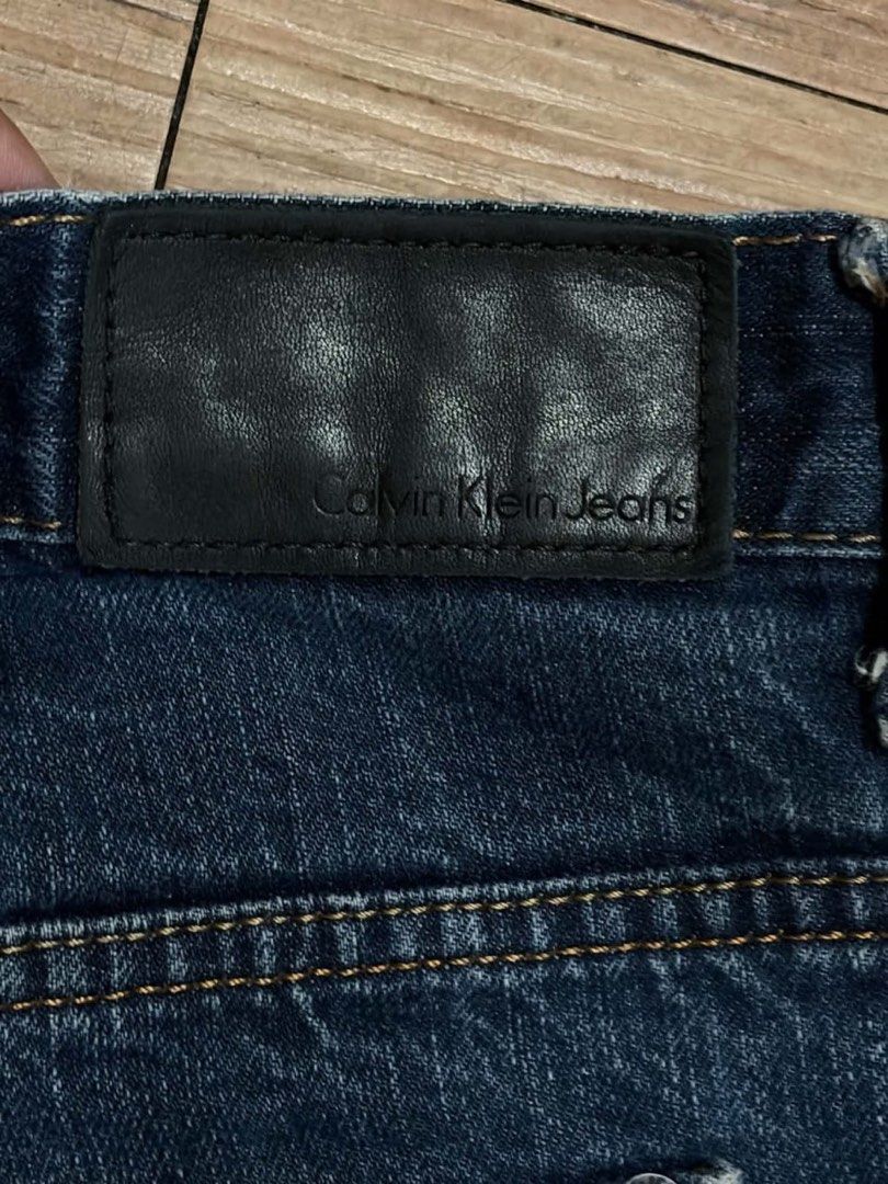 Calvin Klein Jeans Straight Cut Size 36 (Category: Jeans) located in Mandaluyong City. Submitted by zaiampiloquio (Listing ID 1465608488, Image 2). Description: - Brand: Calvin Klein - Color: Dark blue wash with natural thigh and knee fading - Fit: Straight cut - Size: Tag size 36 - Features: Classic five-pocket design, branded button closure, and back leather patch - Condition: Solid everyday denim with regular wear.