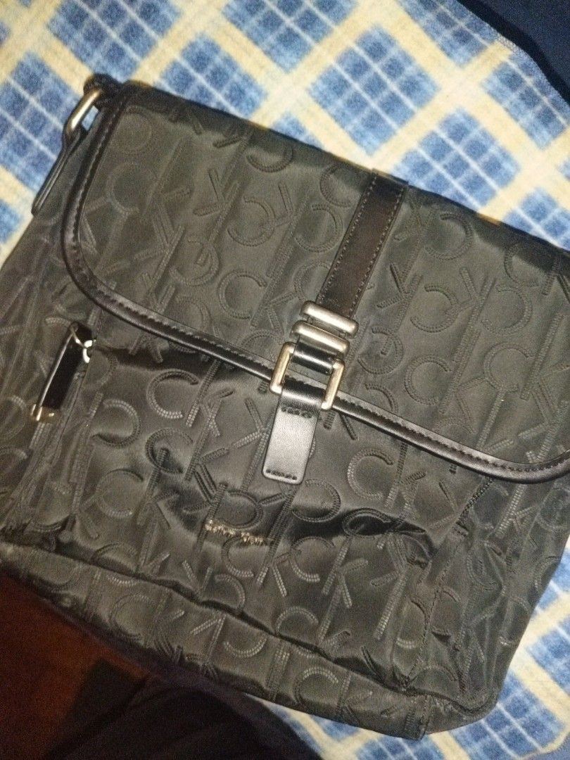 Calvin Klein Monogram Black Messenger Bag (Category: Sling Bags) located in Baguio. Submitted by valenzuela.jc (Listing ID 1465698402, Image 2). Description: Sourced from Canada - Brand: Calvin Klein - Style: Black messenger bag with iconic monogram print - Exterior: Front flap closure with metal buckle, zippered front pocket, and adjustable strap - Interior: Multiple compartments lined with matching monogram fabric - Material: Durable nylon / sy