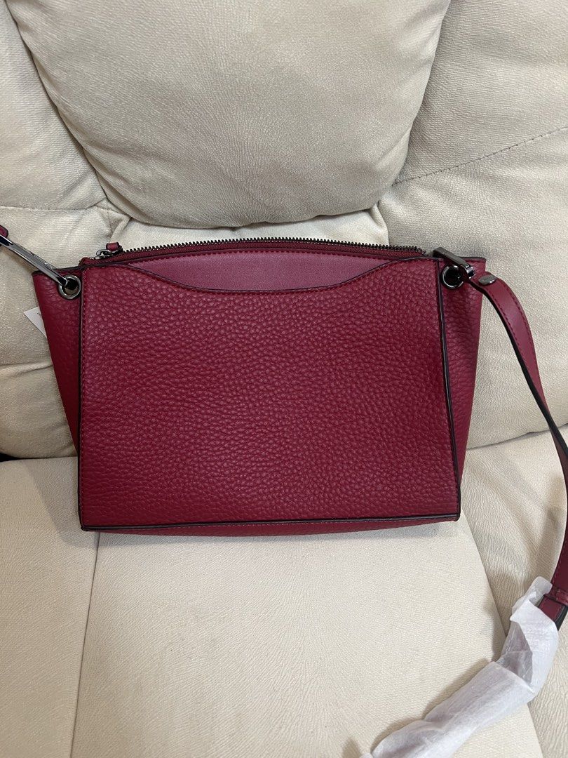 Calvin Klein Red Crossbody Bag (Category: Cross-body Bags) located in Manila. Submitted by pau_only (Listing ID 1465674413, Image 2). Description: - Brand: Calvin Klein - Material: Rich burgundy textured faux leather with dark hardware - Condition: Brand new, stored away with zero wear - Strap: Still wrapped in original packaging, never used - Interior: Dark fabric lining with an extra zip pocket - Closure & Shape: Secure top zip closure with a c