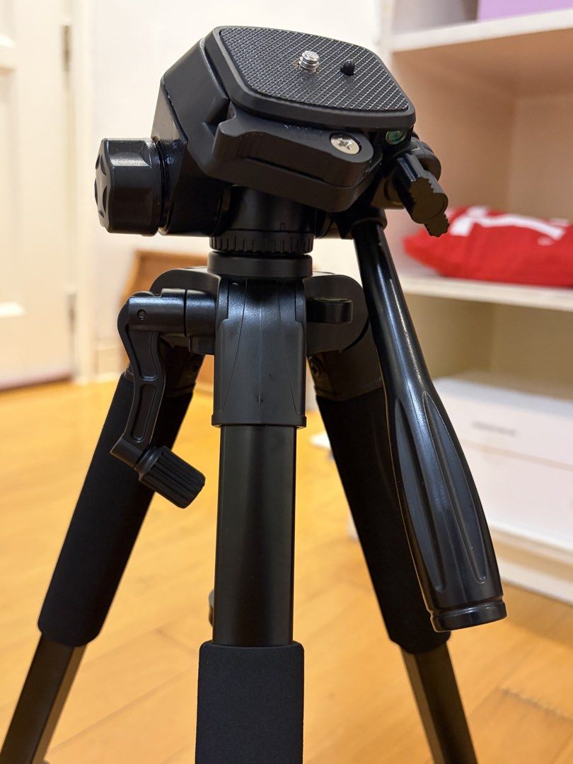 Camera Tripod With Smartphone Mount and Bag (Category: Tripods & Monopods) located in Pasig City. Submitted by sparky.shop (Listing ID 1465674154, Image 3). Description: - Sturdy black tripod suitable for both cameras and smartphones - Smooth pan head and convenient crank handle for easy height adjustment - Comfortable foam grips on legs for secure handling - Comes with a detachable phone mount featuring stylish red accents - Folds down compactly