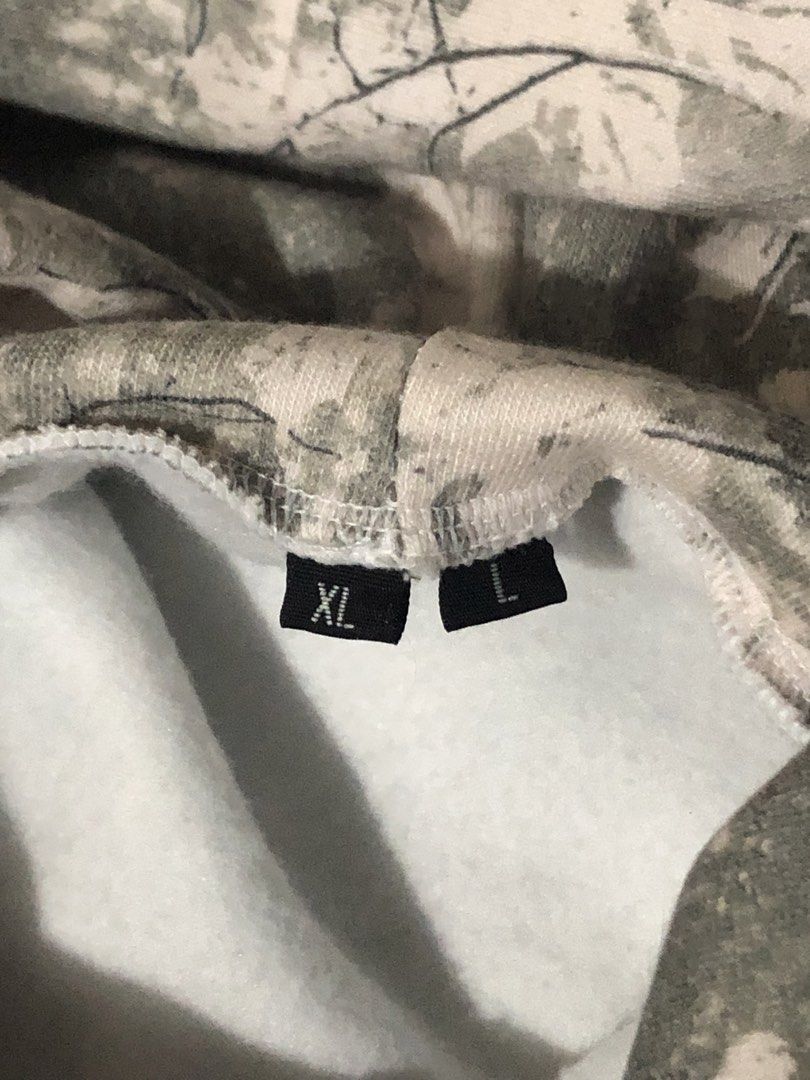 Camo Tree Print Hoodie Sweatshirt (Category: Coats, Jackets and Outerwear) located in Canaman. Submitted by stu333 (Listing ID 1465695383, Image 3). Description: - Design: Grey and white camouflage tree and leaf pattern - Fit: Tagged XL/L (fits comfortably as a pullover) - Comfort: Soft fleece lining inside for extra warmth - Features: Practical front kangaroo pocket, ribbed cuffs and hem - Condition: Warm and ready for cooler days, grab it while