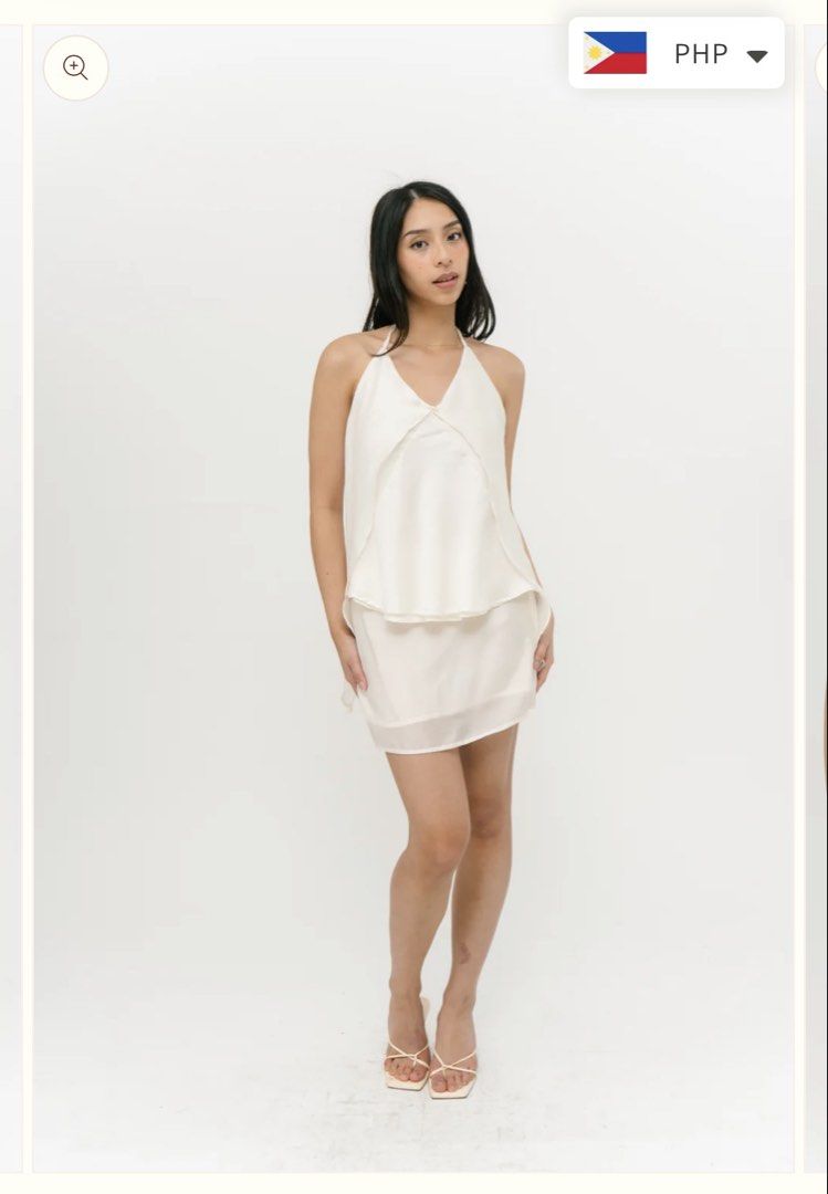 Cariño Iris Top (Category: Sleeveless) located in Manila. Submitted by nicolesdumpsite (Listing ID 1465584979, Image 3). Description: - Color: White - Style: Halter neckline mini dress with overlay top layer and matching skirt - Details: Thin back ties with attached white fabric flowers, lower back zipper closure - Fabric: Smooth, silky, and clean look - Length: Above the knee - Occasion: Perfect for dinners, dates, and night outs USED ONLY ONCE 