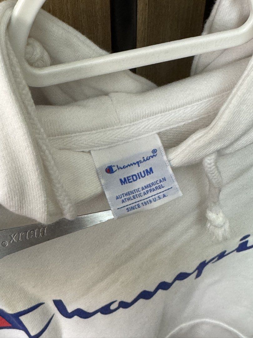 Champion White Hoodie Medium Script Logo (Category: Hoodies) located in Manila. Submitted by prinsloo_ (Listing ID 1465650043, Image 2). Description: - Brand: Champion - Color: White with big script logo across the chest - Size: Medium. Shoulder ~45cm, length ~58.5cm, sleeves ~57.5cm - Material: Comfortable, warm fleece - Features: Front kangaroo pocket, adjustable drawstring hood - Style: Classic casual streetwear - Condition: there are stains d