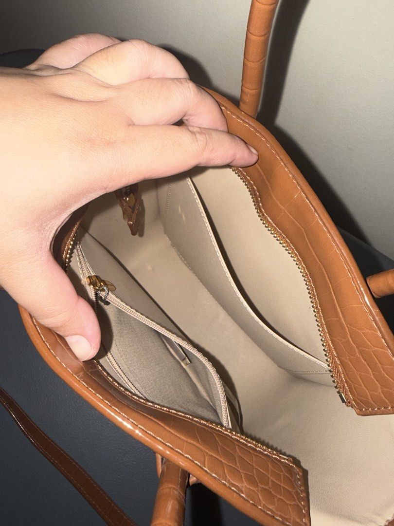 Charles & Keith Brown Crocodile Effect Tote Bag (Category: Tote Bags) located in Las Pinas. Submitted by p.noona (Listing ID 1465698136, Image 2). Description: - Brown faux leather with a glossy crocodile embossed finish - Structured vertical tote style with dual top handles - Includes a matching adjustable shoulder strap with gold hardware - Features gold-tone protective feet on the bottom - Clean light beige interior with an open slip pocket an