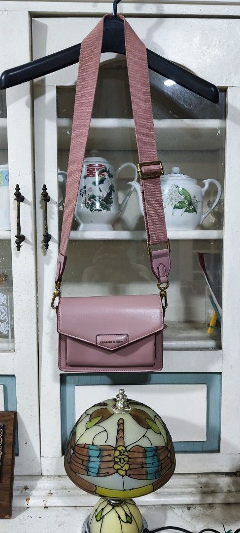Charles & Keith Pink Crossbody Bag (Category: Cross-body Bags) located in Manila. Submitted by shawn0320_fish (Listing ID 1465630763, Image 1). Description: - Brand: Charles & Keith - Style: Pink crossbody bag with flap closure and magnetic snap - Strap: Wide, adjustable matching pink canvas strap - Hardware & Details: Gold-toned hardware and front pocket with branded plaque - Perfect for daily use or casual outings! Nsa photos na po issue sa loo
