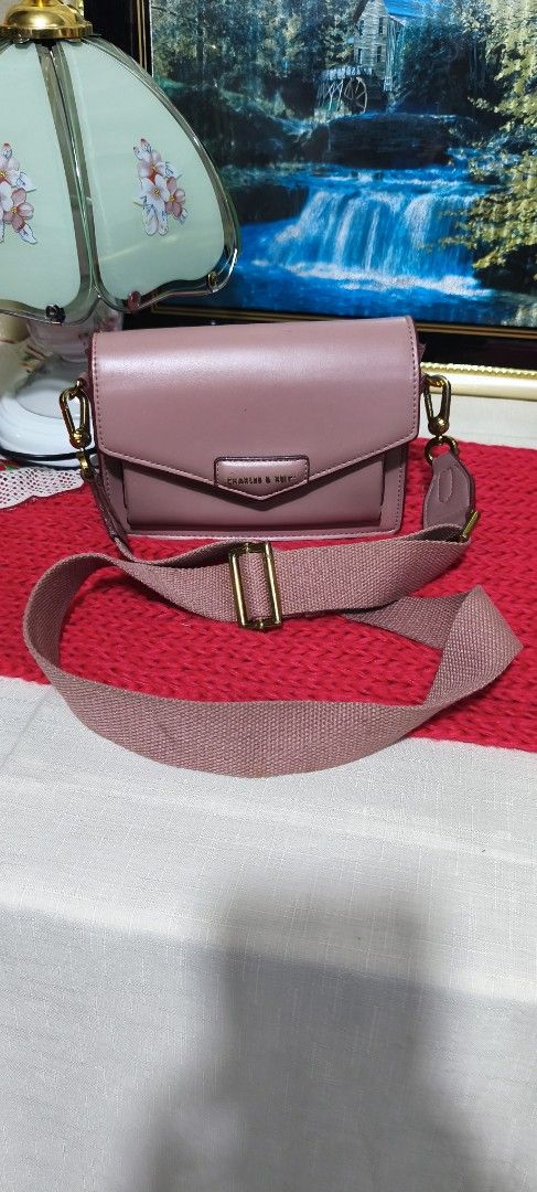Charles & Keith Pink Crossbody Bag (Category: Cross-body Bags) located in Manila. Submitted by shawn0320_fish (Listing ID 1465630763, Image 2). Description: - Brand: Charles & Keith - Style: Pink crossbody bag with flap closure and magnetic snap - Strap: Wide, adjustable matching pink canvas strap - Hardware & Details: Gold-toned hardware and front pocket with branded plaque - Perfect for daily use or casual outings! Nsa photos na po issue sa loo