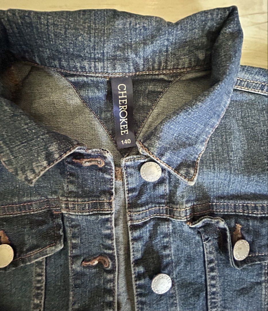 Cherokee Denim Jacket Size 140 (Category: Babies & Kids Fashion) located in Manila. Submitted by ai010 (Listing ID 1465630043, Image 2). Description: - Brand/Model: Cherokee Denim Jacket - Size: 140 - Color: Classic Blue Denim - Closure: Button-up front with metal buttons and button cuffs - Pockets: Dual chest flap pockets with button closures - Details: Structured collar and traditional contrast stitching throughout.