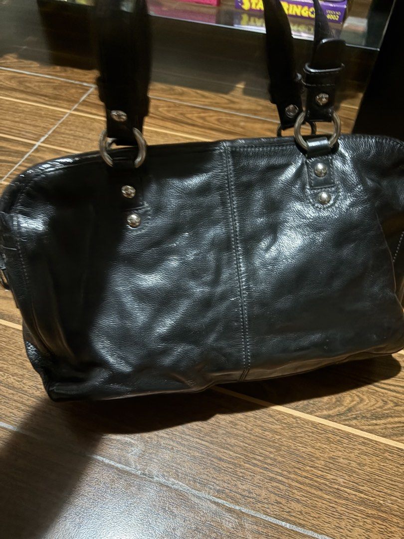 Coach Black Leather Handbag with Turnlock Closure (Category: Luxury Bags & Wallets) located in Bulacan. Submitted by love2loved (Listing ID 1465669985, Image 2). Description: Black Coach leather handbag with double top handles and silver hardware. Front flap pocket featuring a turnlock closure and embossed Coach logo. Side gussets with ring details and dual zippered main compartment. Includes cute plush charms and pom-poms attached to the front r