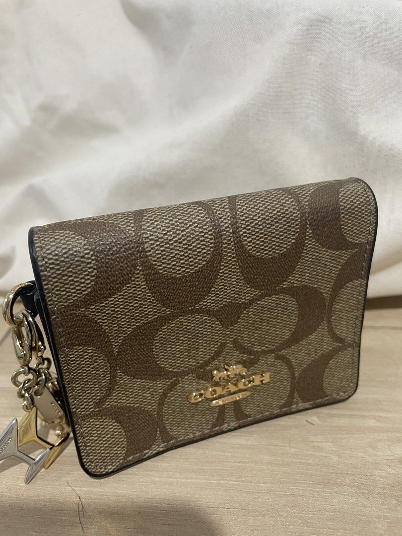Coach Signature Canvas Mini Wallet with Charm (Category: Wallets & Card holders) located in Cordova. Submitted by fiercedragon.47e450 (Listing ID 1465710312, Image 1). Description: - Authentic Coach wallet in classic signature brown canvas - Elegant gold-tone hardware with a secure snap closure - Interior includes a card slot and a convenient cash compartment - Comes with an adorable attached bear and key pendant charm - Compact size, ideal for s