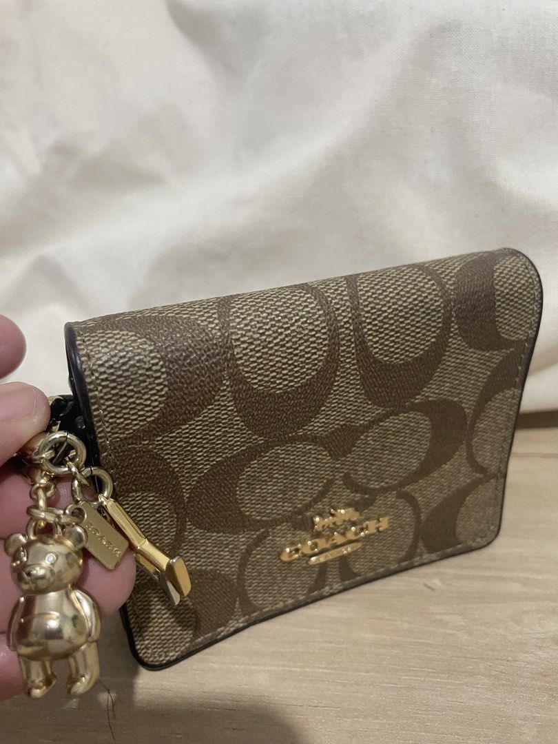 Coach Signature Canvas Mini Wallet with Charm (Category: Wallets & Card holders) located in Cordova. Submitted by fiercedragon.47e450 (Listing ID 1465710312, Image 2). Description: - Authentic Coach wallet in classic signature brown canvas - Elegant gold-tone hardware with a secure snap closure - Interior includes a card slot and a convenient cash compartment - Comes with an adorable attached bear and key pendant charm - Compact size, ideal for s